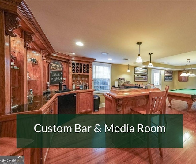 bar featuring black dishwasher, wood finished floors, hanging light fixtures, indoor wet bar, and recessed lighting