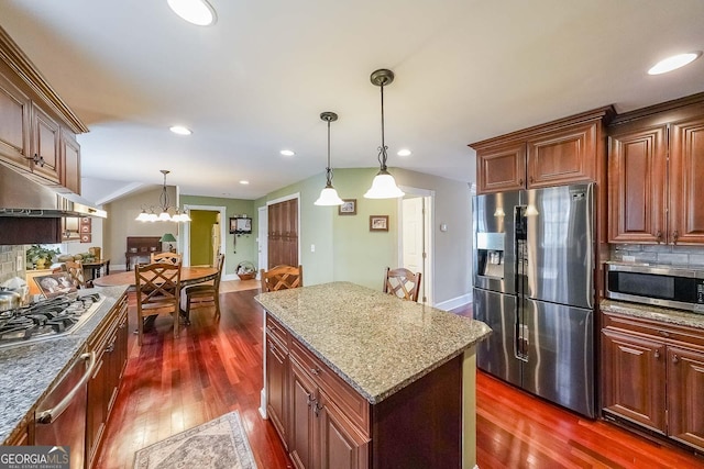 kitchen with light stone counters, pendant lighting, tasteful backsplash, appliances with stainless steel finishes, and dark wood-type flooring