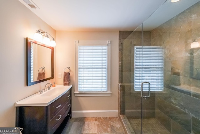 bathroom with plenty of natural light, a shower stall, baseboards, and vanity