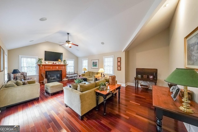 living room with baseboards, a ceiling fan, a glass covered fireplace, lofted ceiling, and dark wood-style flooring