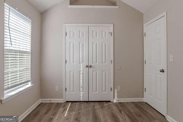 unfurnished bedroom with lofted ceiling, hardwood / wood-style floors, and a closet