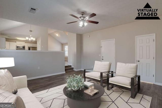 living room featuring ceiling fan with notable chandelier, vaulted ceiling, and light wood-type flooring