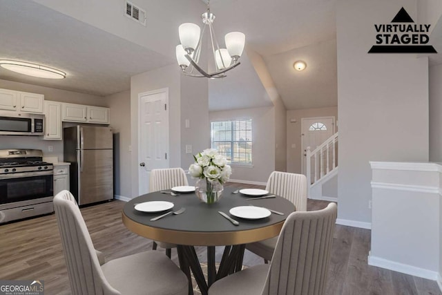 dining room featuring vaulted ceiling, light hardwood / wood-style floors, and a chandelier