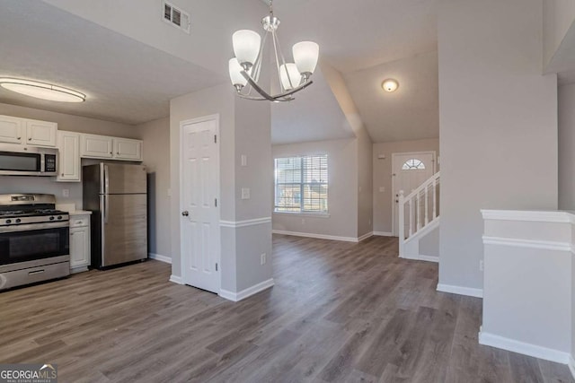 kitchen with stainless steel appliances, pendant lighting, white cabinets, and light wood-type flooring