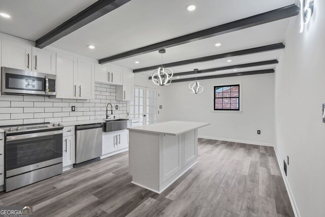 kitchen featuring sink, a kitchen island, white cabinets, and appliances with stainless steel finishes