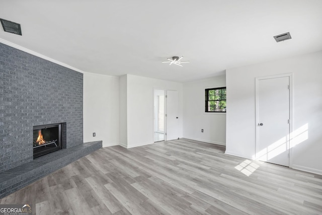 unfurnished living room featuring a fireplace, ceiling fan, and light wood-type flooring