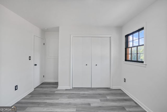 unfurnished bedroom with a closet and light wood-type flooring