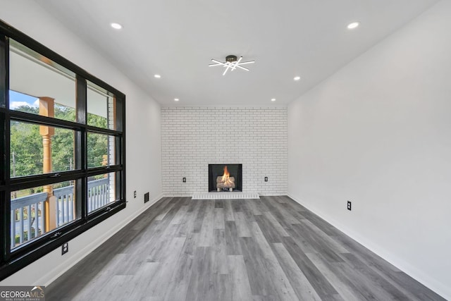 unfurnished living room with brick wall, hardwood / wood-style floors, and a fireplace