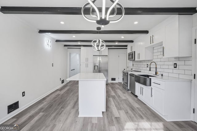 kitchen with pendant lighting, sink, appliances with stainless steel finishes, tasteful backsplash, and white cabinets