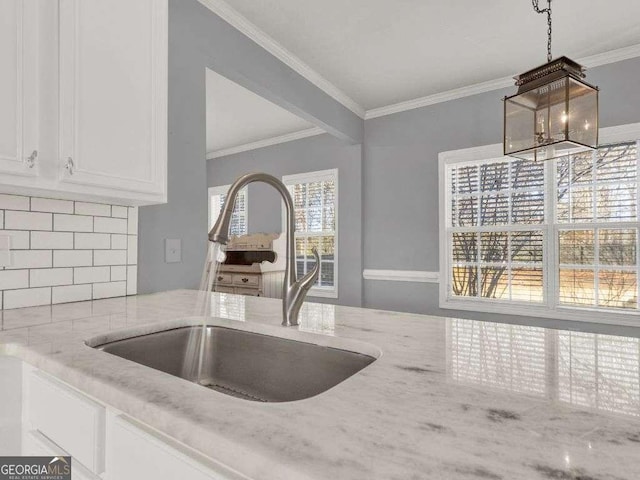 kitchen with sink, white cabinetry, tasteful backsplash, ornamental molding, and light stone countertops