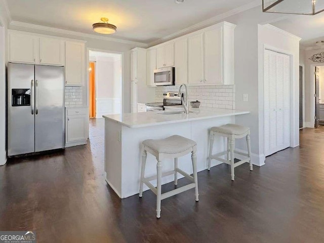 kitchen featuring white cabinetry, crown molding, stainless steel appliances, and kitchen peninsula