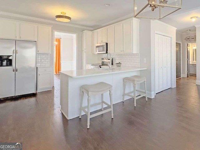 kitchen with ornamental molding, stainless steel appliances, kitchen peninsula, and white cabinets