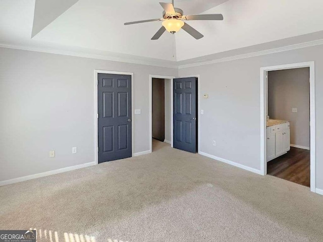 unfurnished bedroom featuring a tray ceiling, crown molding, and carpet flooring