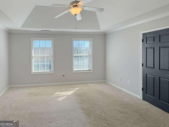 spare room featuring ceiling fan, ornamental molding, a raised ceiling, and light carpet