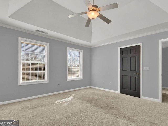 spare room featuring crown molding, ceiling fan, carpet, a tray ceiling, and vaulted ceiling