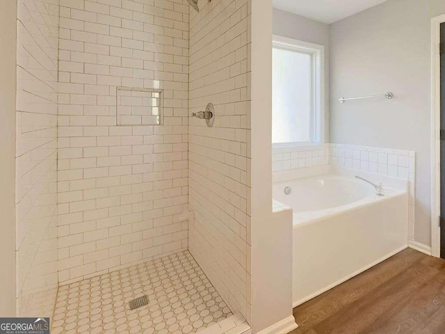 bathroom with wood-type flooring and shower with separate bathtub