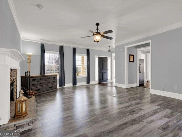 unfurnished living room featuring a stone fireplace, dark wood-type flooring, ornamental molding, and ceiling fan