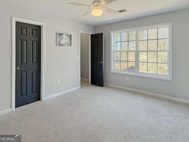 unfurnished bedroom featuring ceiling fan, light colored carpet, and multiple windows