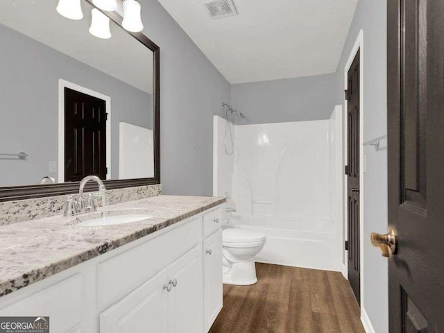 full bathroom with shower / bathing tub combination, vanity, wood-type flooring, and toilet