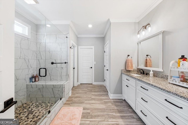 bathroom with crown molding, a marble finish shower, vanity, wood finished floors, and baseboards