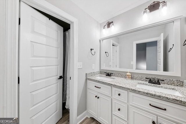 full bath with double vanity, a sink, and wood finished floors