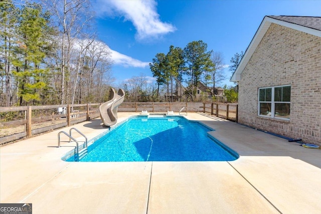 view of swimming pool with a fenced in pool, fence, a water slide, and a patio