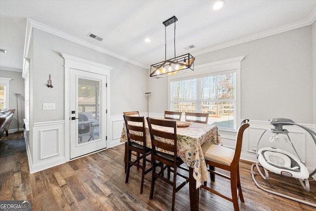 dining space featuring a wainscoted wall, ornamental molding, dark wood-type flooring, and visible vents