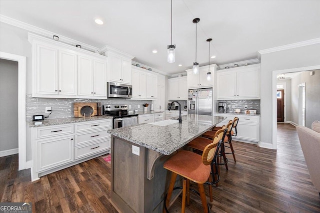 kitchen with stainless steel appliances, a kitchen island with sink, pendant lighting, and white cabinets