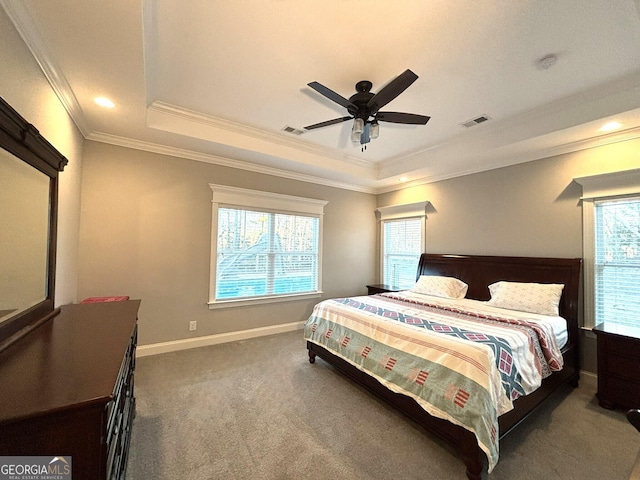 carpeted bedroom with a tray ceiling, visible vents, crown molding, and baseboards