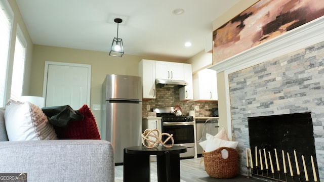 kitchen with white cabinetry, light wood-type flooring, appliances with stainless steel finishes, pendant lighting, and decorative backsplash