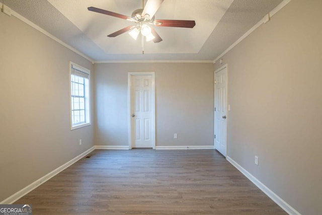 unfurnished bedroom with a tray ceiling, ornamental molding, ceiling fan, and hardwood / wood-style flooring