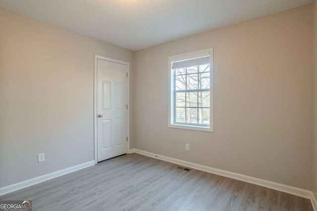 spare room featuring a textured ceiling and light wood-type flooring