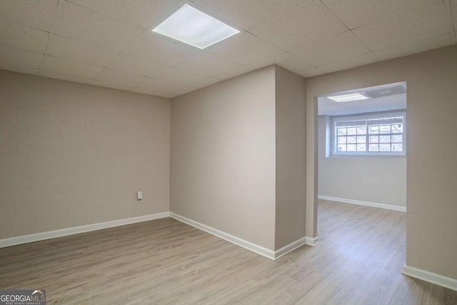 spare room featuring a drop ceiling and light wood-type flooring