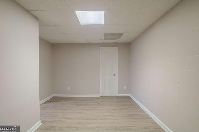 spare room featuring a drop ceiling and light hardwood / wood-style flooring