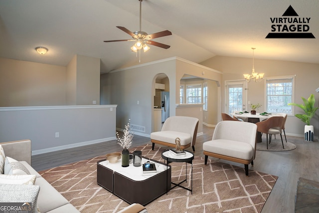 living room featuring hardwood / wood-style flooring, ceiling fan with notable chandelier, and vaulted ceiling