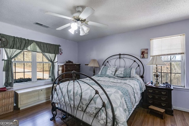 bedroom with ceiling fan, dark hardwood / wood-style floors, and a textured ceiling