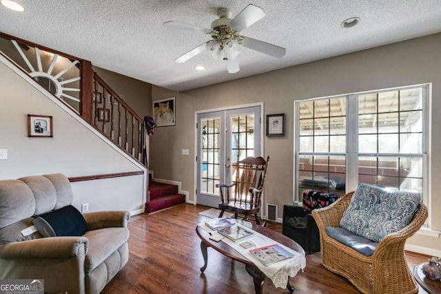 living room with french doors, ceiling fan, dark hardwood / wood-style flooring, and a textured ceiling