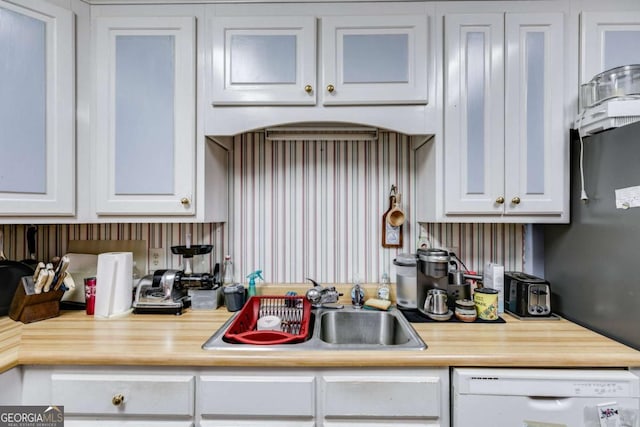 kitchen featuring sink, white cabinets, and white dishwasher