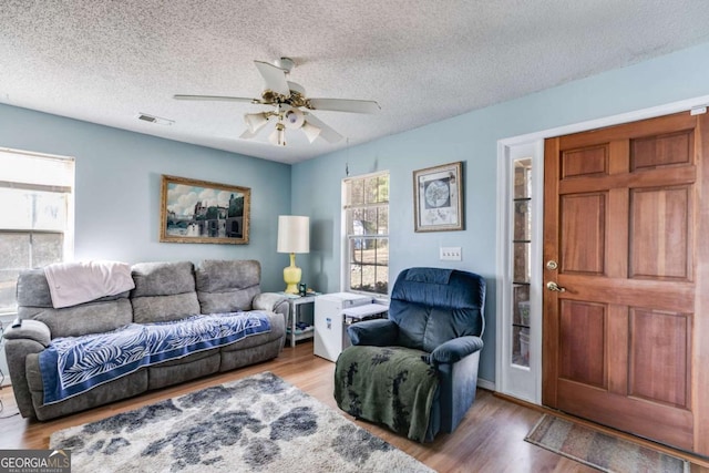 living room featuring hardwood / wood-style flooring, a textured ceiling, and ceiling fan