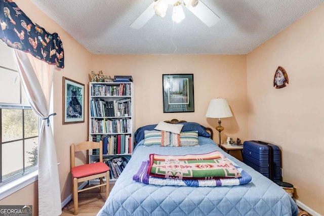 bedroom with ceiling fan, hardwood / wood-style floors, and a textured ceiling