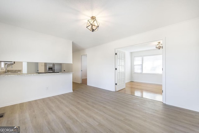 unfurnished living room with sink and light hardwood / wood-style floors