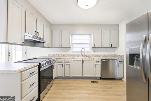 kitchen featuring appliances with stainless steel finishes, sink, light hardwood / wood-style flooring, and kitchen peninsula