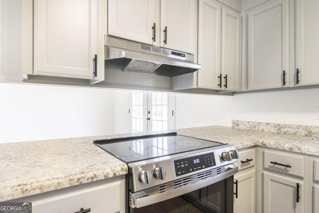 kitchen with stainless steel range with electric stovetop and light stone countertops