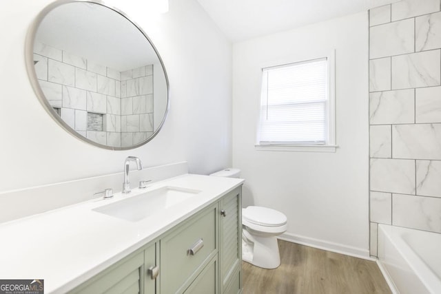 full bathroom featuring vanity, hardwood / wood-style floors, tiled shower / bath, and toilet