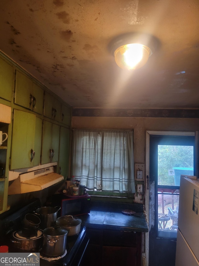 kitchen featuring green cabinetry, refrigerator, and electric range oven