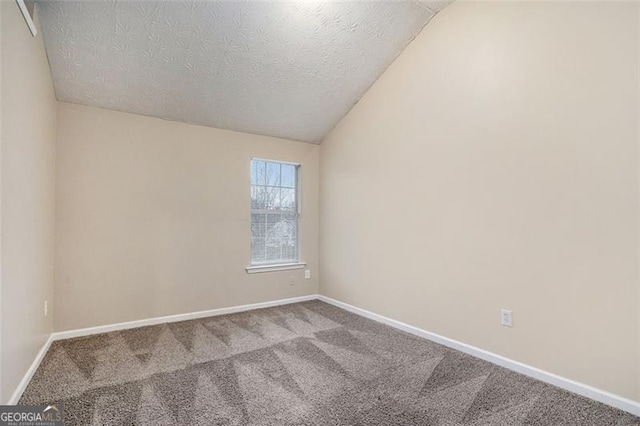 unfurnished room featuring carpet floors, a textured ceiling, and vaulted ceiling