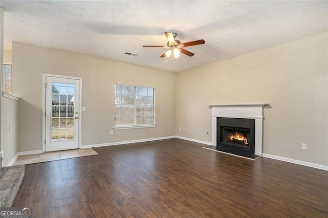 unfurnished living room with dark wood-type flooring, ceiling fan, and a textured ceiling