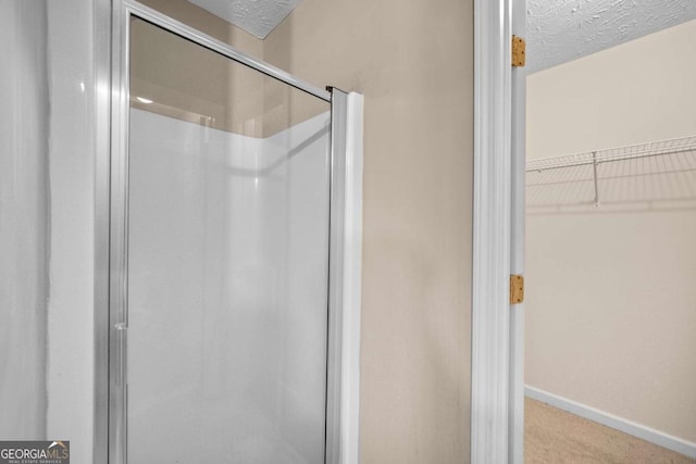 bathroom with a shower with shower door and a textured ceiling