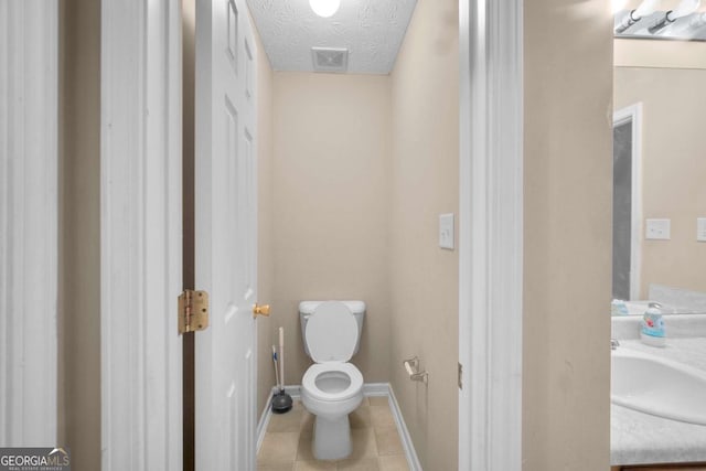 bathroom featuring tile patterned flooring, vanity, a textured ceiling, and toilet