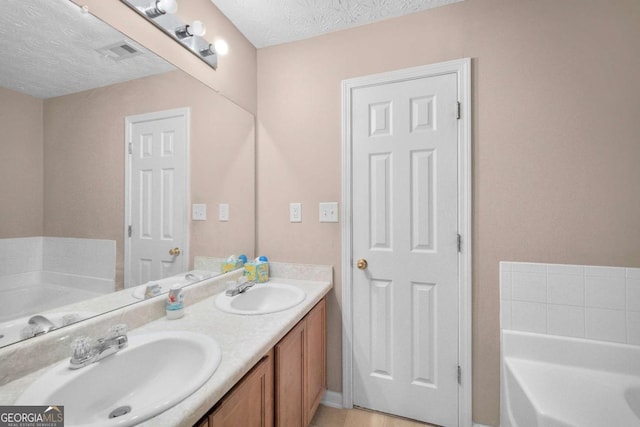 bathroom with vanity, a bathtub, and a textured ceiling